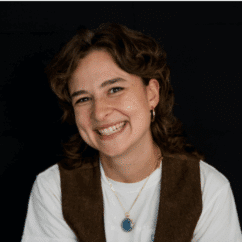 Sophie Sandberg smiling at the camera against a black background.